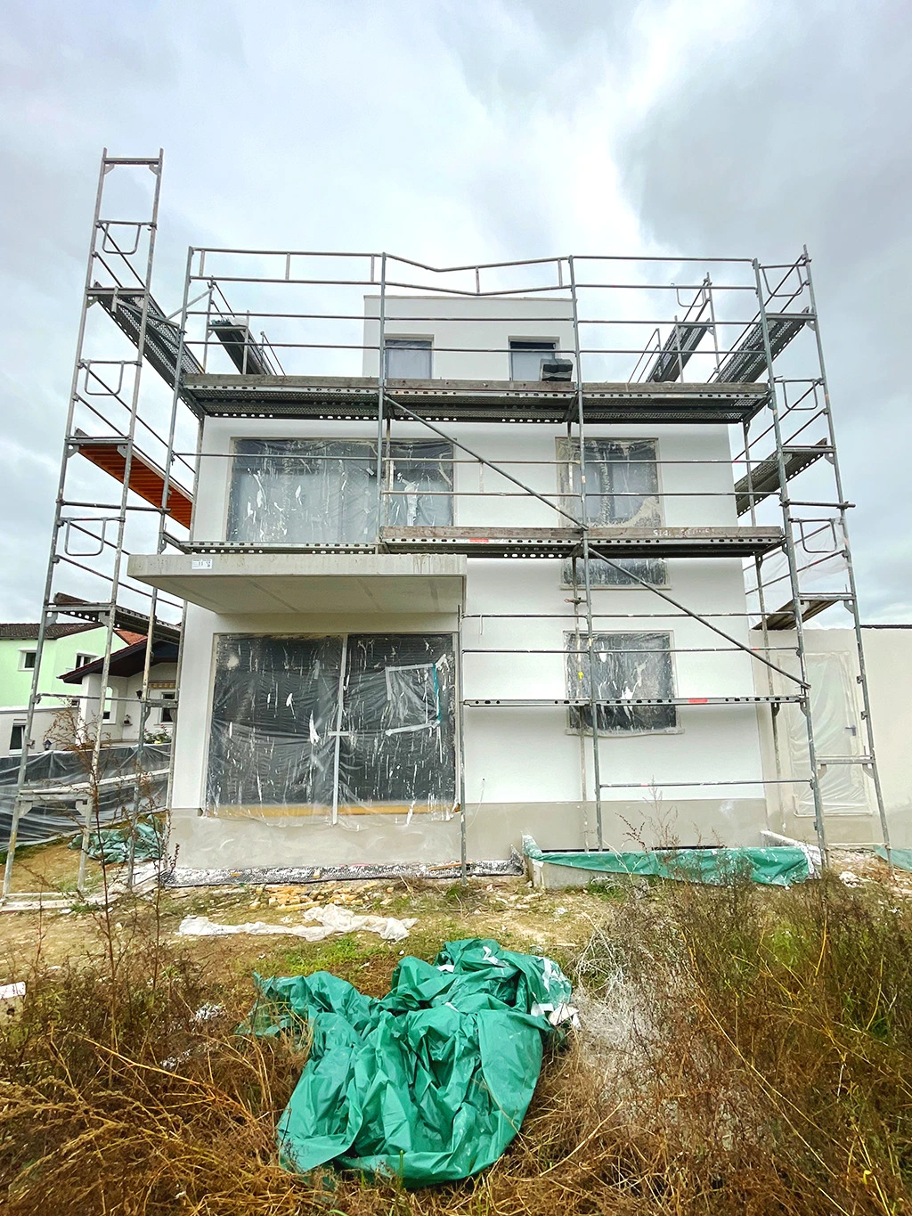 Wohnhaus im Bau mit Fassadengerüst und Schutzabdeckungen – Fassadensanierung oder Neubau durch Top Facility