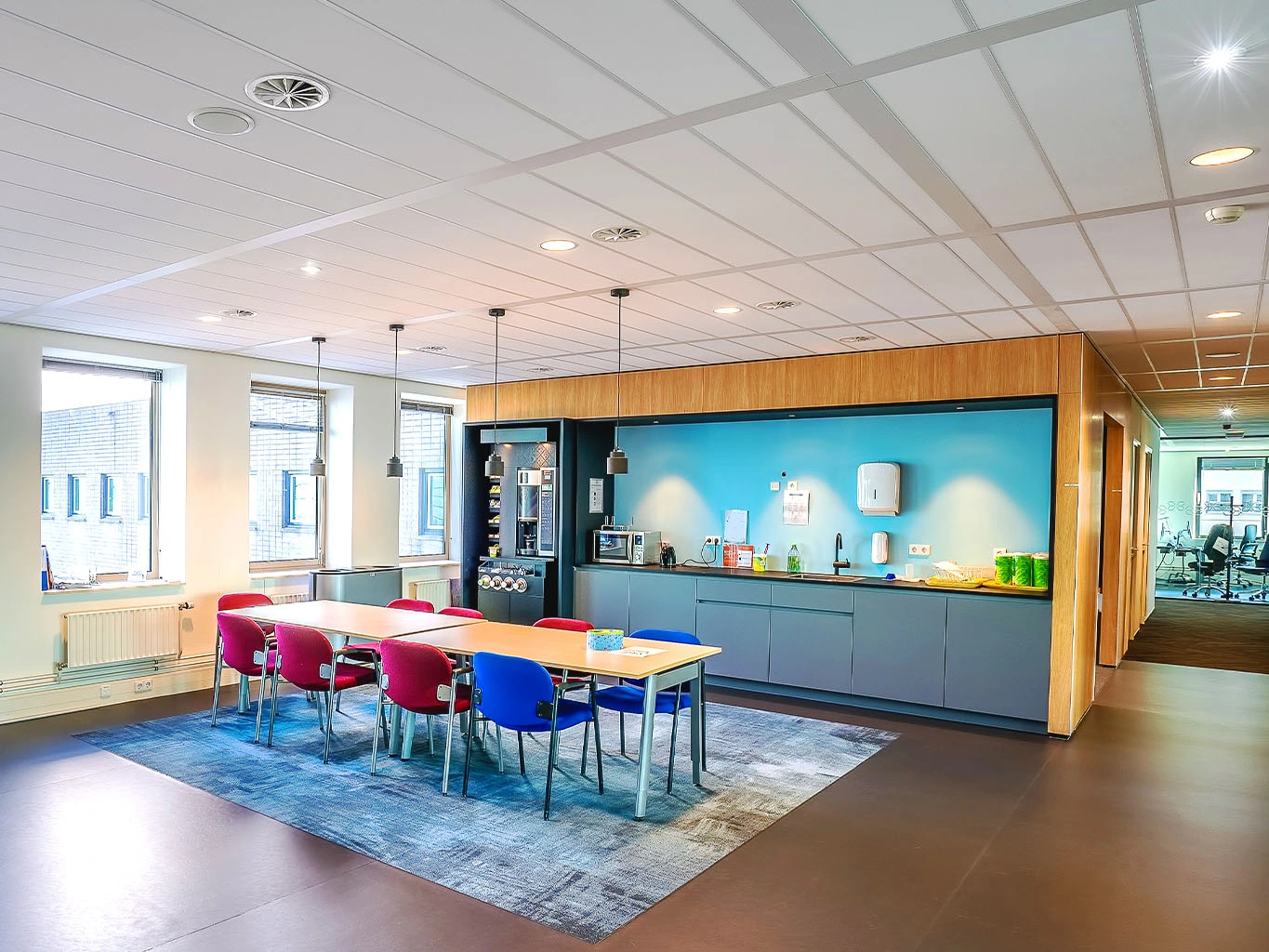 Modernisierter Pausenraum mit Einbauküche, bunten Stühlen und freundlicher Farbgestaltung in einem Bürogebäude