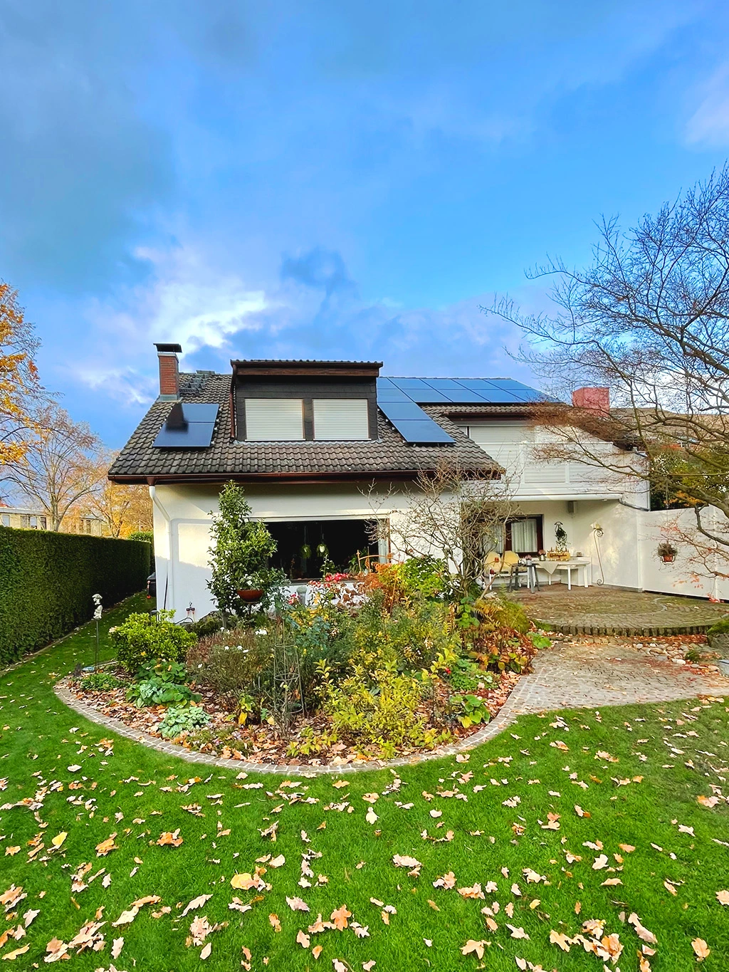 Einfamilienhaus mit gepflegtem Garten, Herbstlaub auf dem Rasen und Solaranlage auf dem Dach – ein Projekt von Top Facility